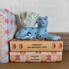 Ceramic cat-shaped planter on top of books with a polka dot book beside it.