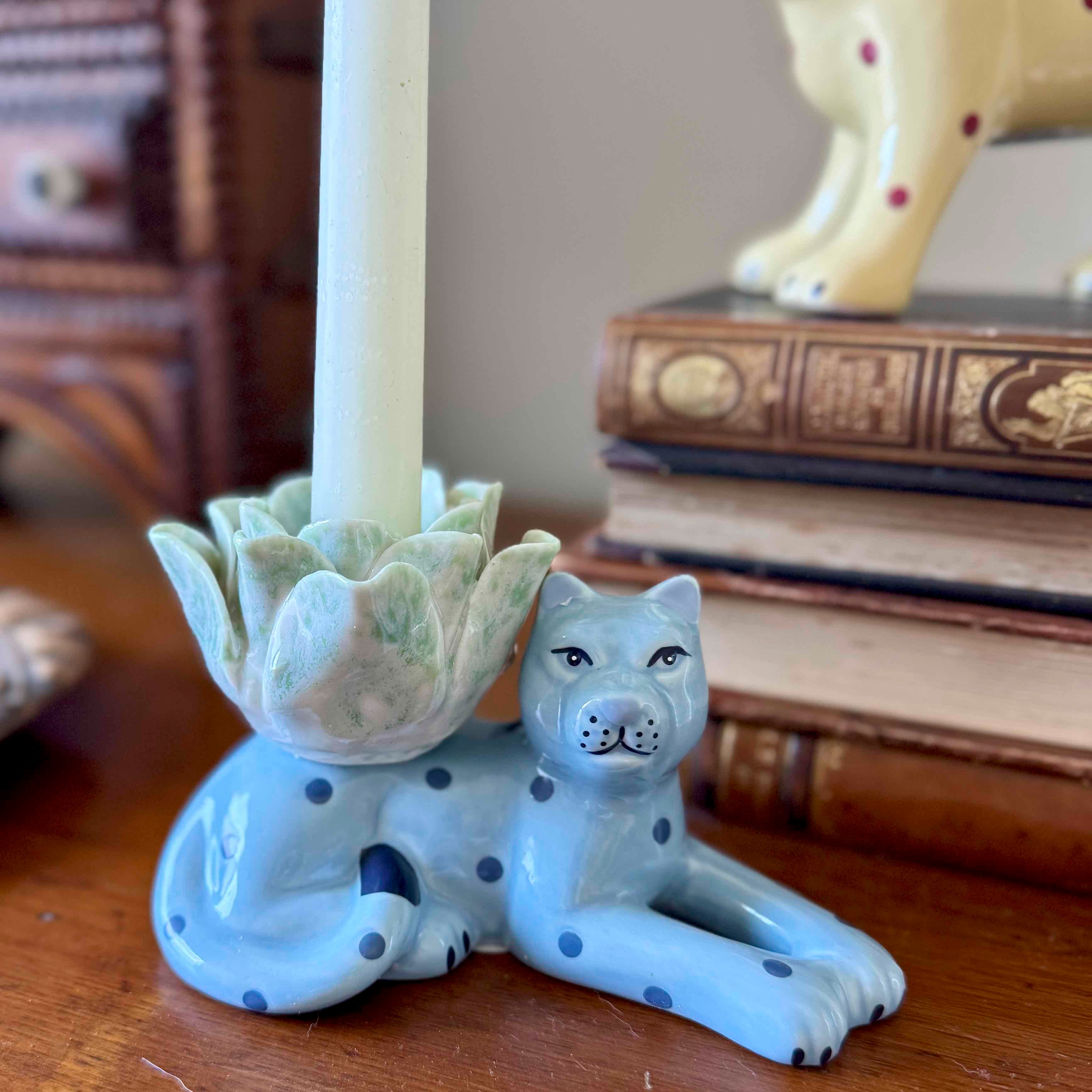 Ceramic candle holder shaped like a dog with a candle inside, on a wooden surface.