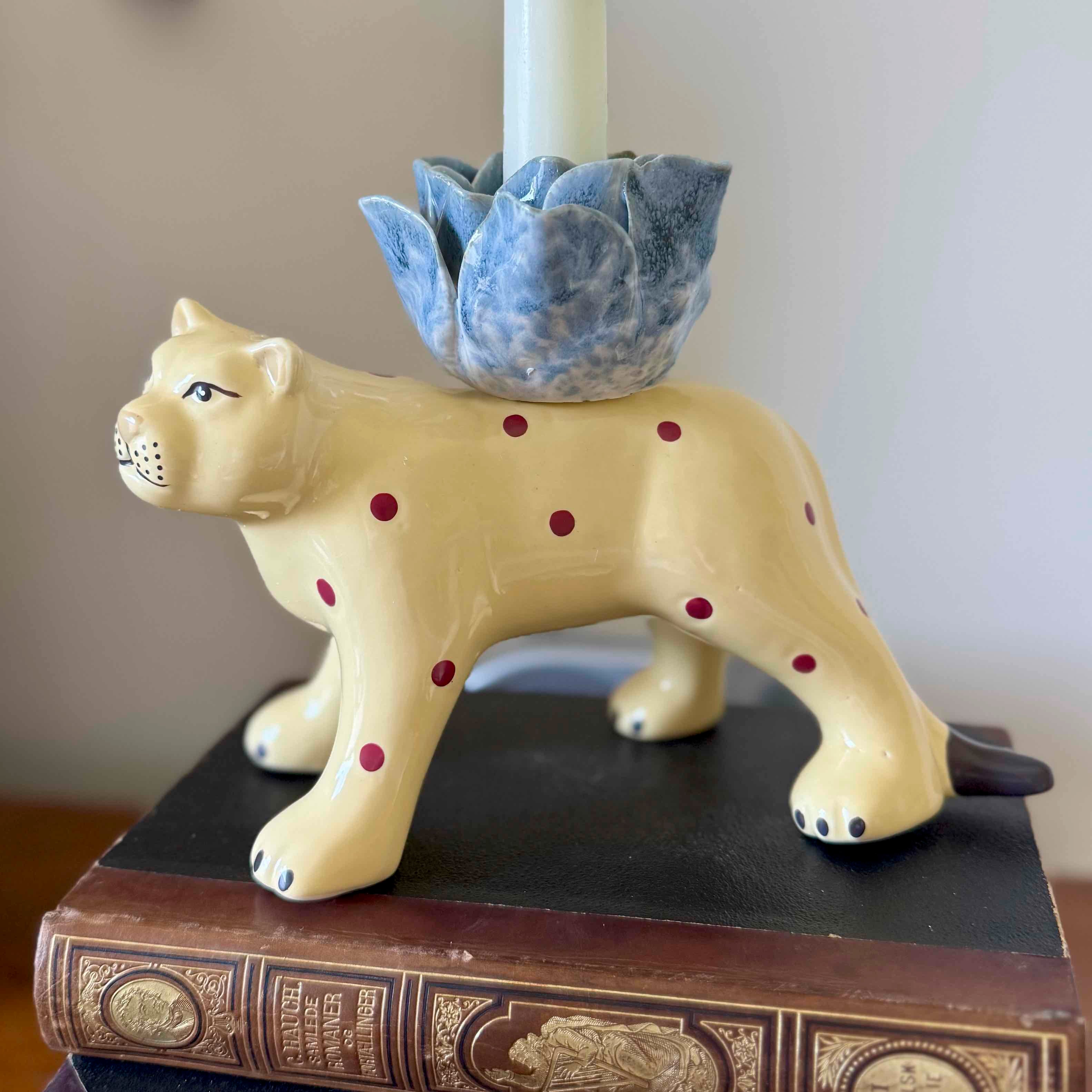 Ceramic animal-shaped candle holder with a blue flowerpot on top, placed on an old book.