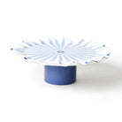 Blue cake stand with a white scalloped edge on a white background