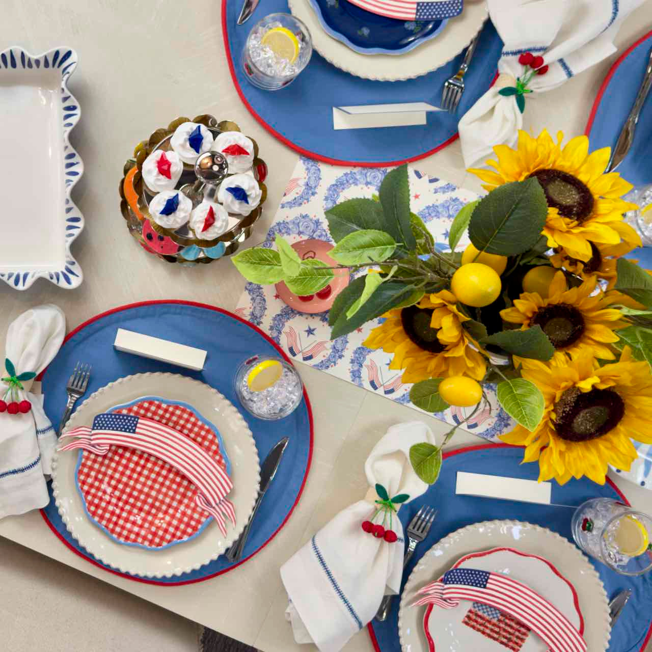 Dining table setting with American flag-themed plates, sunflowers, and decorative items.