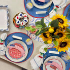 Dining table setting with American flag-themed plates, sunflowers, and decorative items.