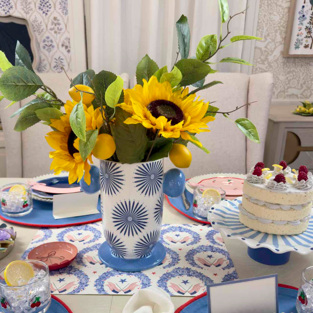 Decorative table setting with sunflowers in a patterned vase, cake, and colorful plates.