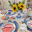Dining table set for a celebration with plates, napkins, and a vase of sunflowers.