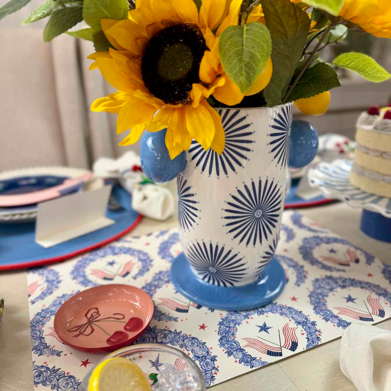 Decorative table setting with sunflowers in a patterned vase on a festive tablecloth.