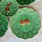 Set of green ceramic plates with animal designs on a wooden surface