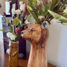 Wooden bear figurine with a vase of flowers in a home setting