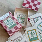 Playing cards with botanical designs and checkered box on a wooden surface