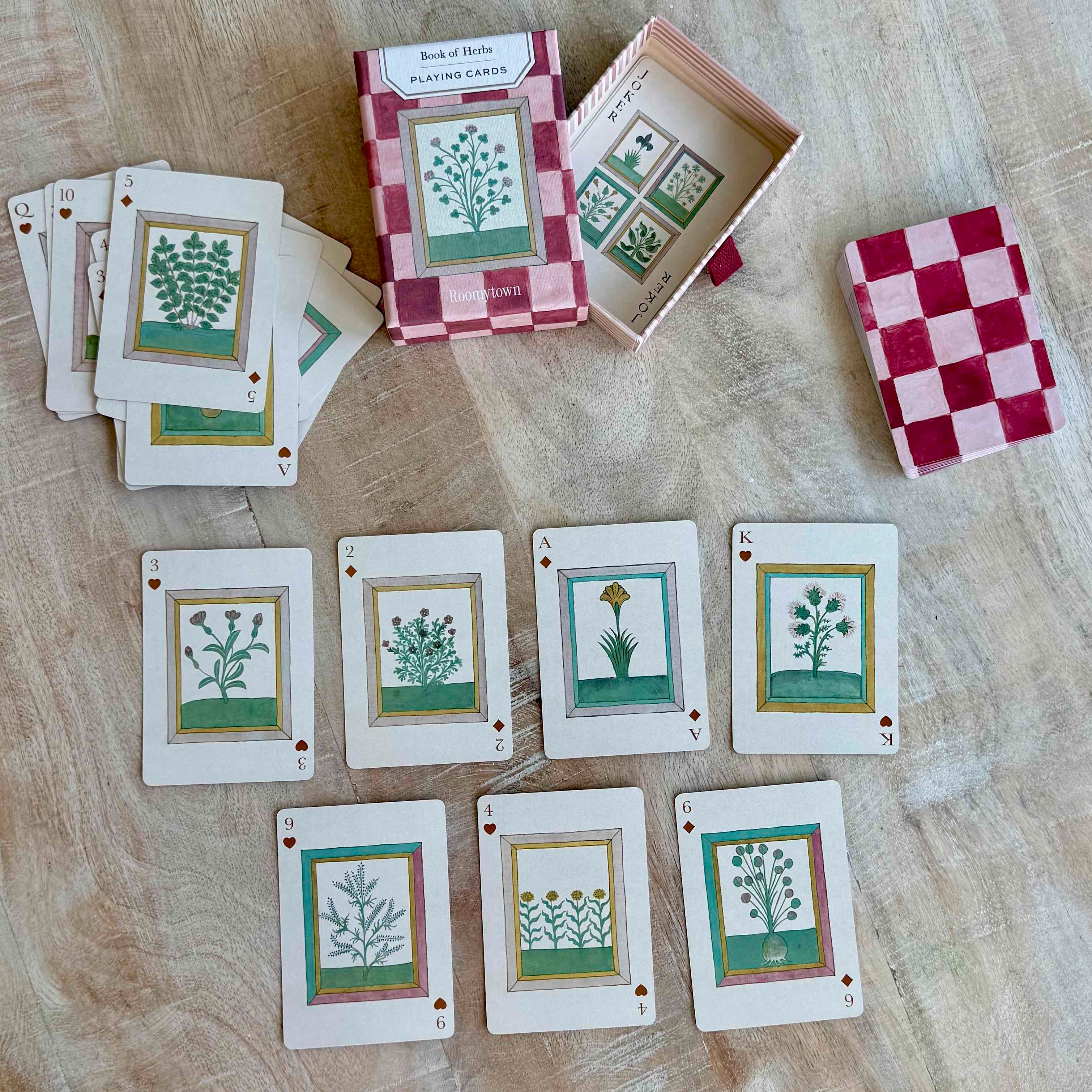 Set of playing cards with botanical designs on a wooden surface