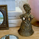 Bronze figurine of a woman with intricate details on a wooden surface.