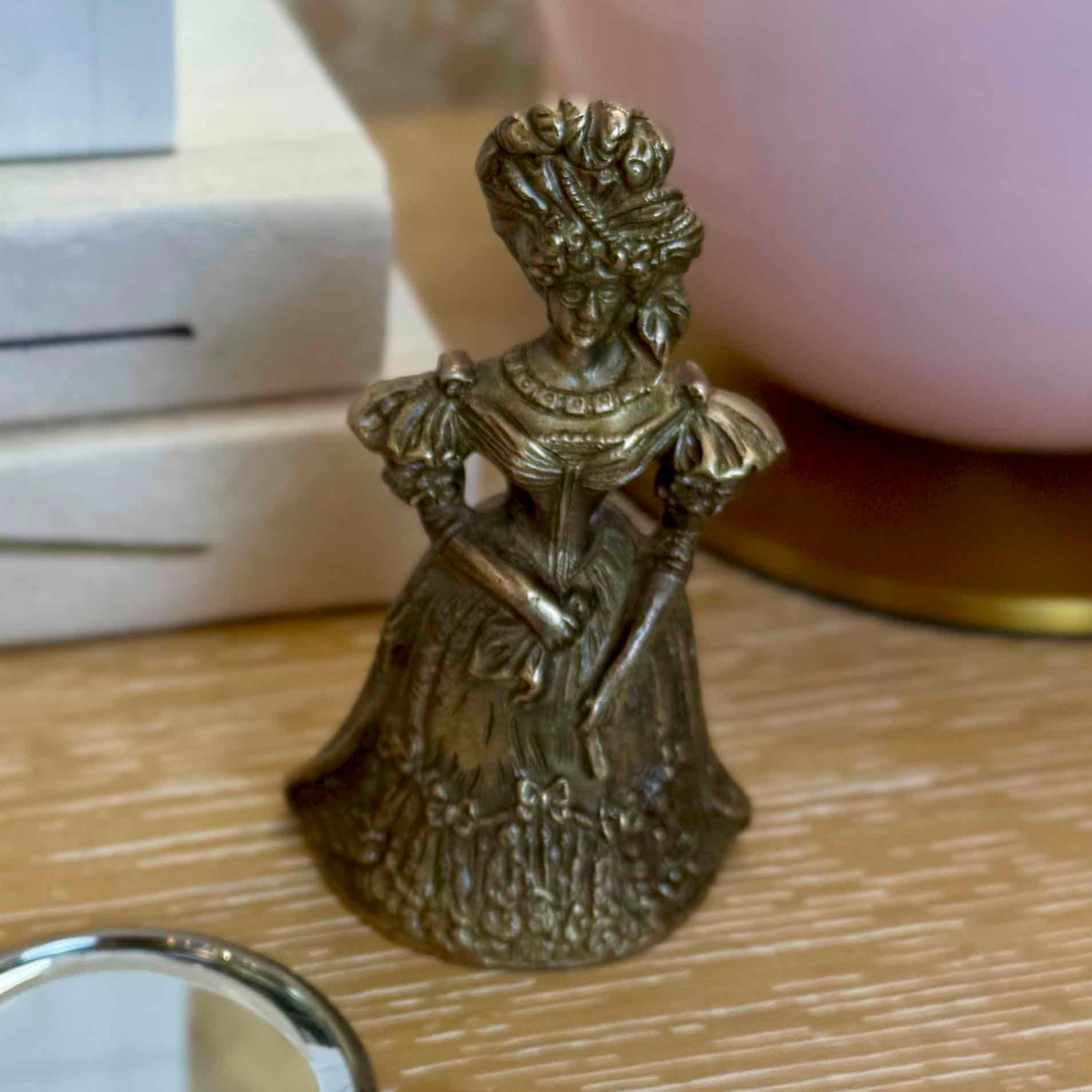 Bronze figurine of a woman in an elaborate dress on a wooden surface
