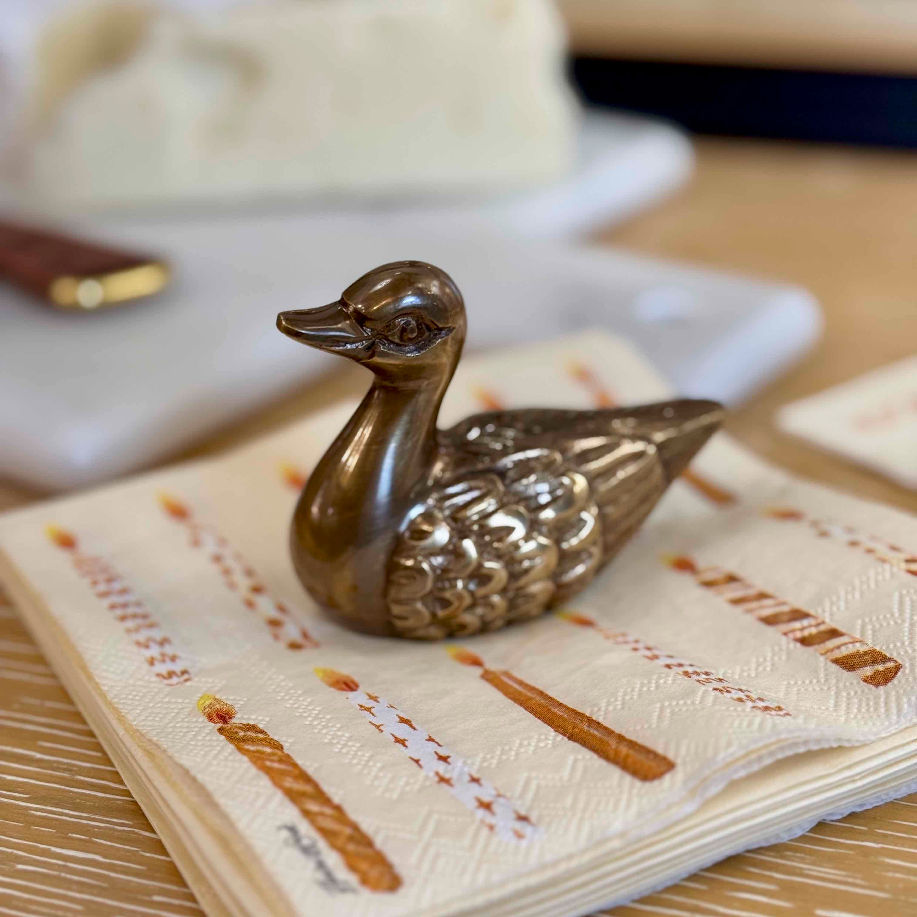 Bronze duck-shaped object on a folded napkin with text