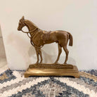 Bronze horse statue on a textured surface with a neutral background