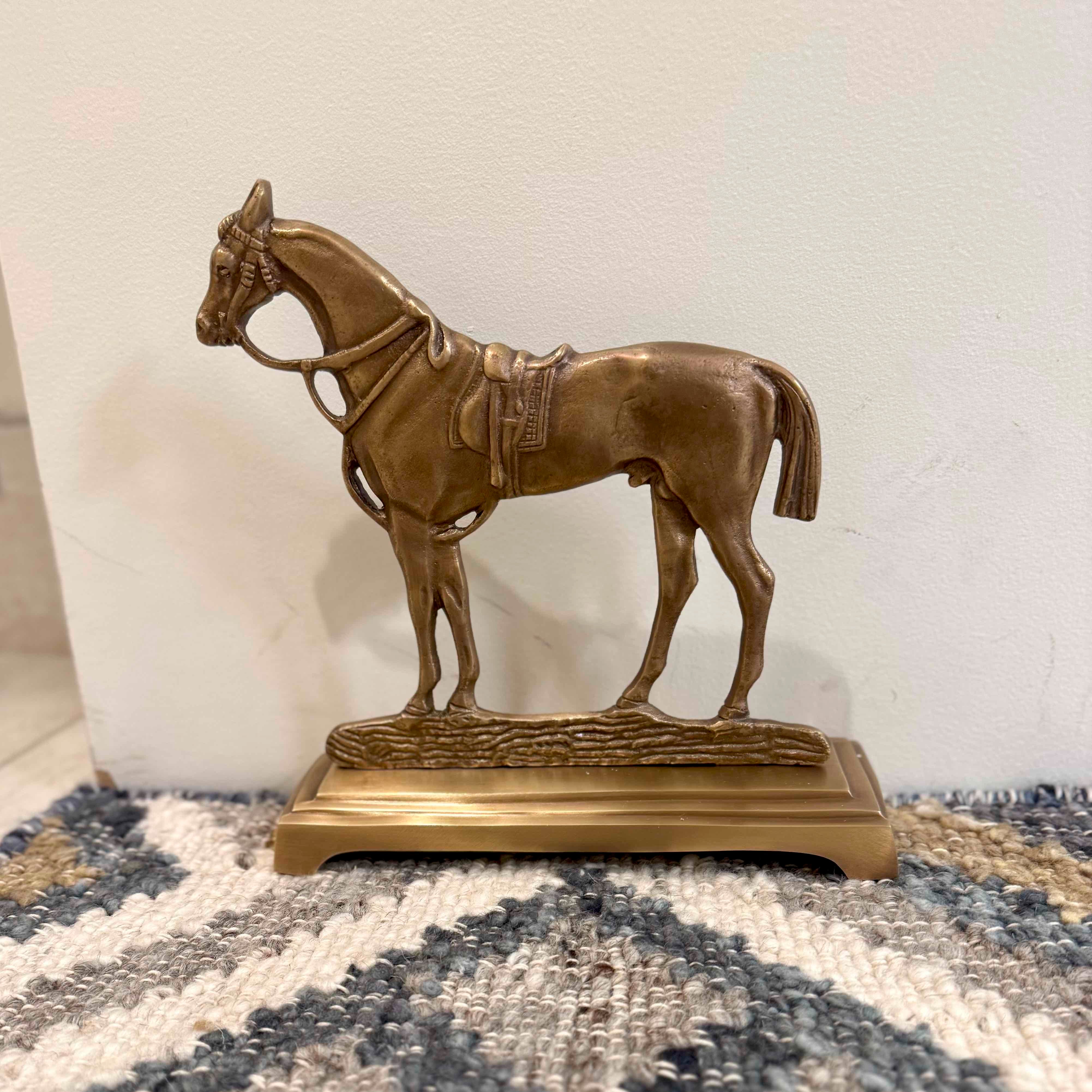 Bronze horse statue on a textured surface with a neutral background