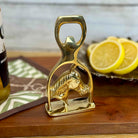 Gold horse-shaped bottle opener on a wooden surface with lemons in the background