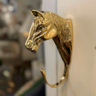 Gold horse head hook on a white wall