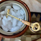 Decorative smoking pipe with wooden and gold accents on a bed of ice.