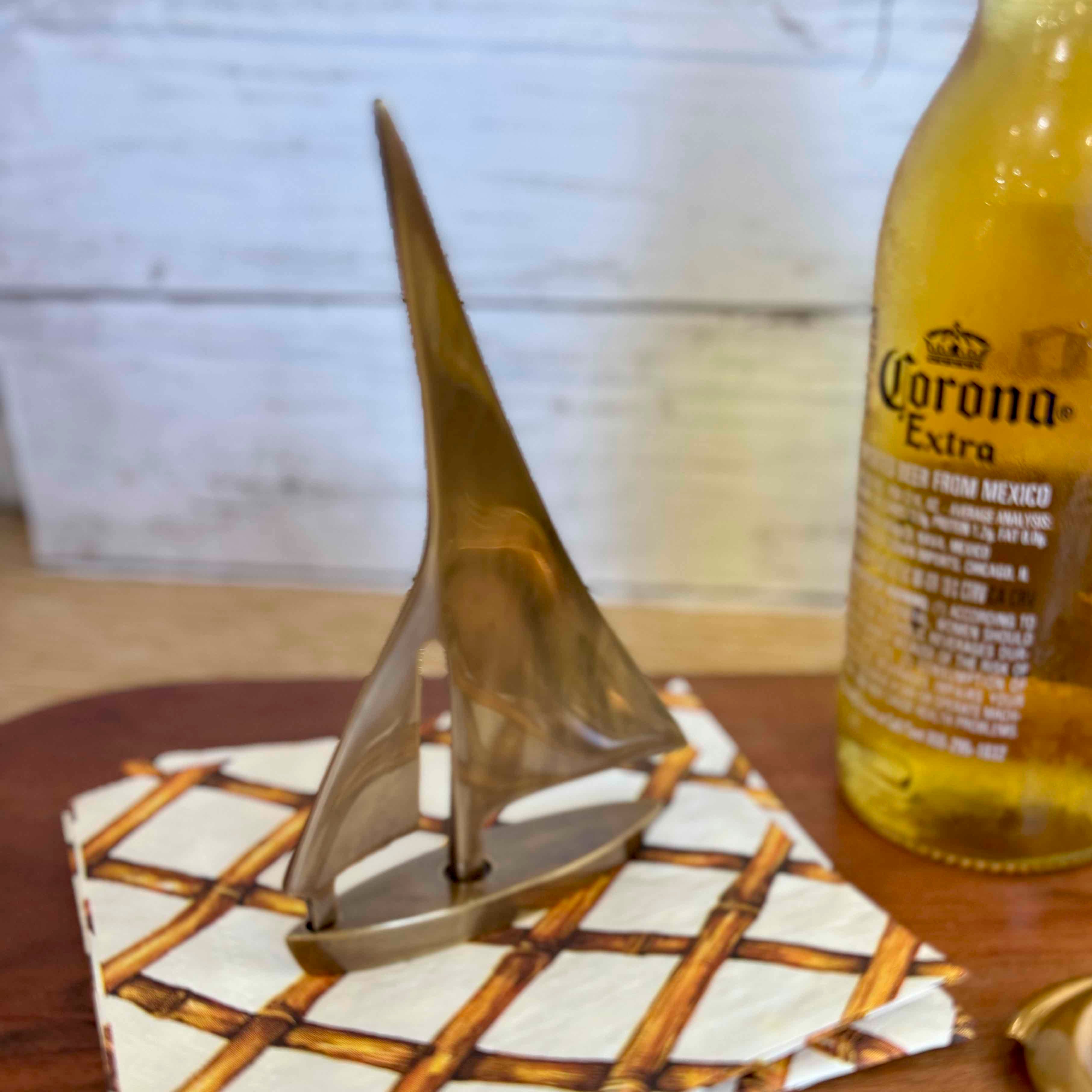 Small sailboat model on a coaster with a Corona Extra beer bottle in the background.