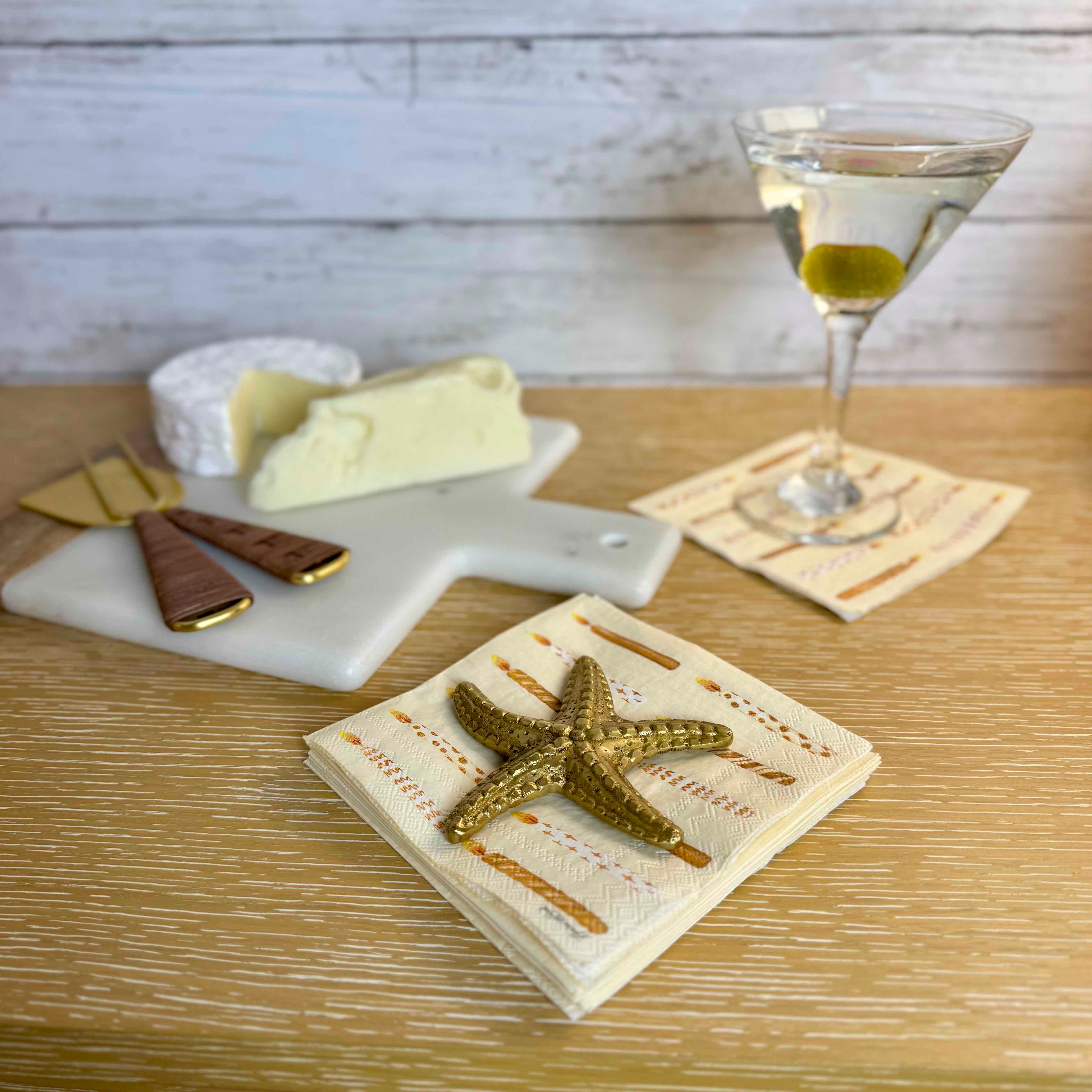 Starfish napkin holder on a table with cheese and a glass of white wine.