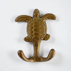 A brass turtle-shaped wall hook with a textured shell and flared wings, mounted on a plain white background.