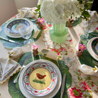Easter-themed table setting with decorative plates, flowers, and place settings.