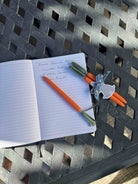 Open notebook with pens and a glass on a metal surface