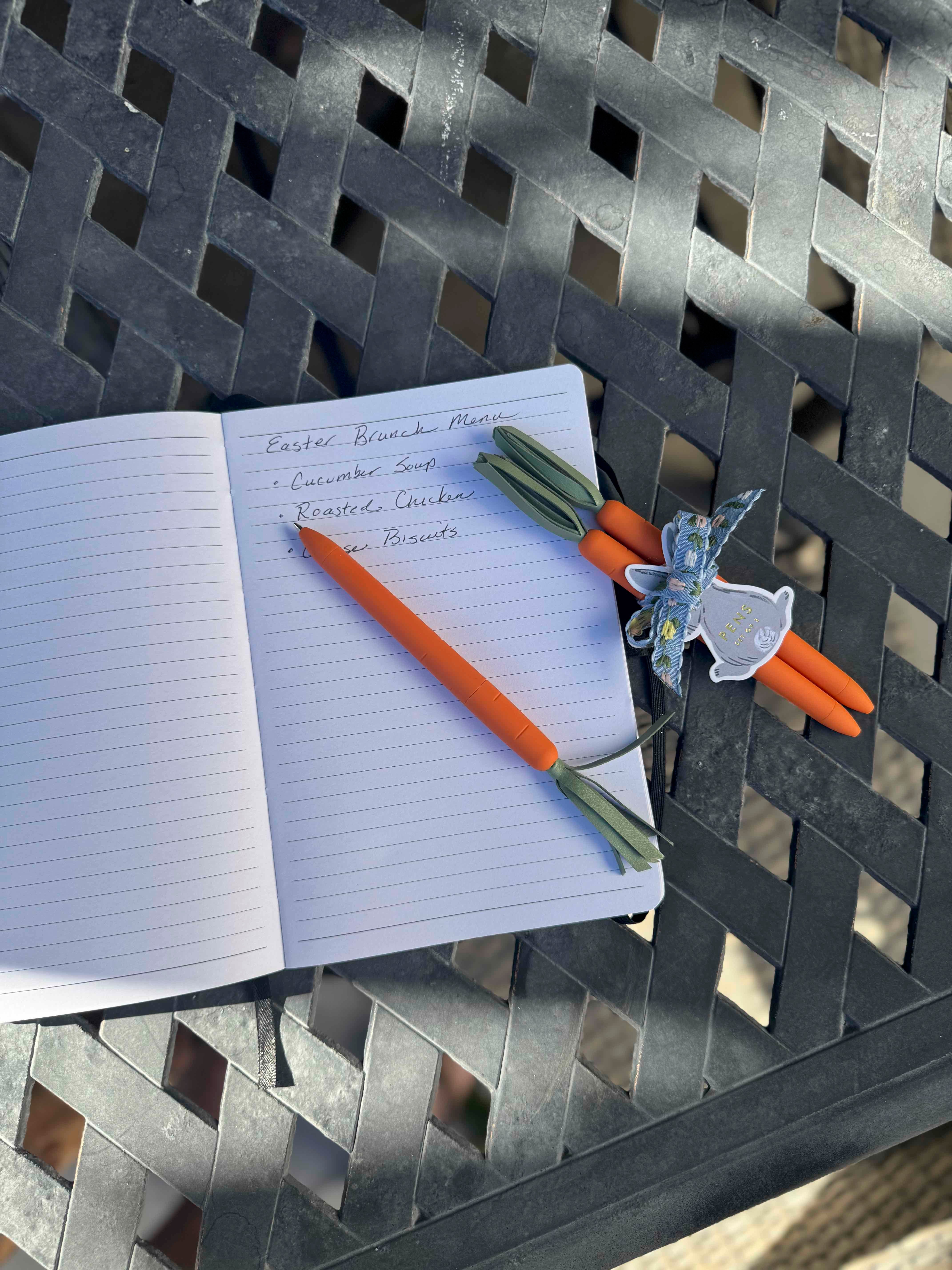 Open notebook with pens and a glass on a metal surface