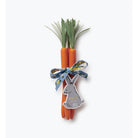Three carrots with green tops tied together with a ribbon featuring a rabbit charm on a white background.
