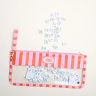 Pink and orange striped pouch with miniature tiles on a light gray background