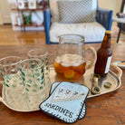 Tray with glasses, pitcher of iced tea, bottle, and 'Sardines' sign on a wooden table.