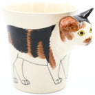 Cat-shaped mug with a calico cat design on a white background
