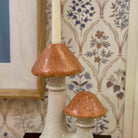 Ceramic mushroom-shaped candle holders with a decorative wall in the background