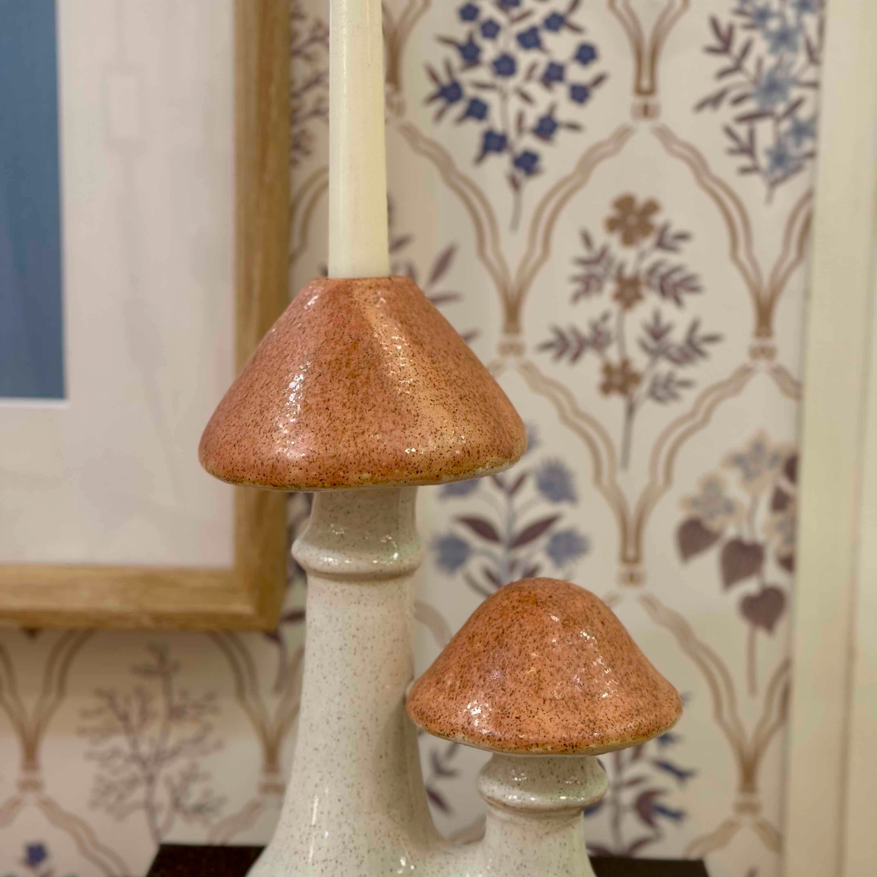 Ceramic mushroom-shaped candle holders with a decorative wall in the background