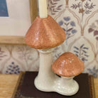 Ceramic mushroom candle holder on a surface with a patterned background