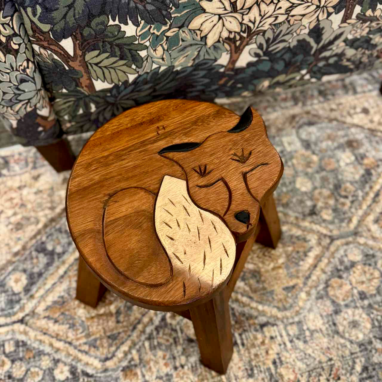 Wooden fox-shaped stool on a patterned rug