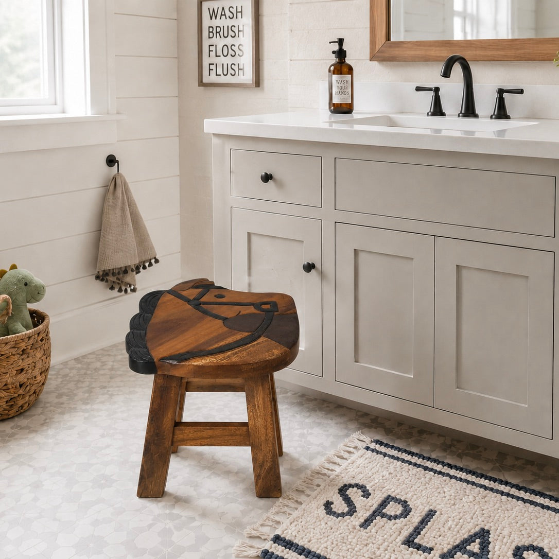 A rustic wooden bathroom stool with a carved animal face design sits in front of a white vanity in a bright, modern bathroom.