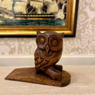 Wooden owl figurine on a surface with a decorative background