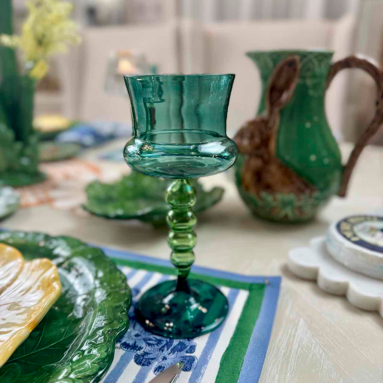 Green glass candle holder on a table with decorative items