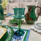 Green glass candle holder on a table with decorative items