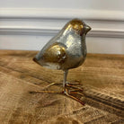 Decorative bird figurine with gold and silver finish on a wooden surface