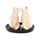Two ceramic dog-shaped salt and pepper shakers on a black base against a white background