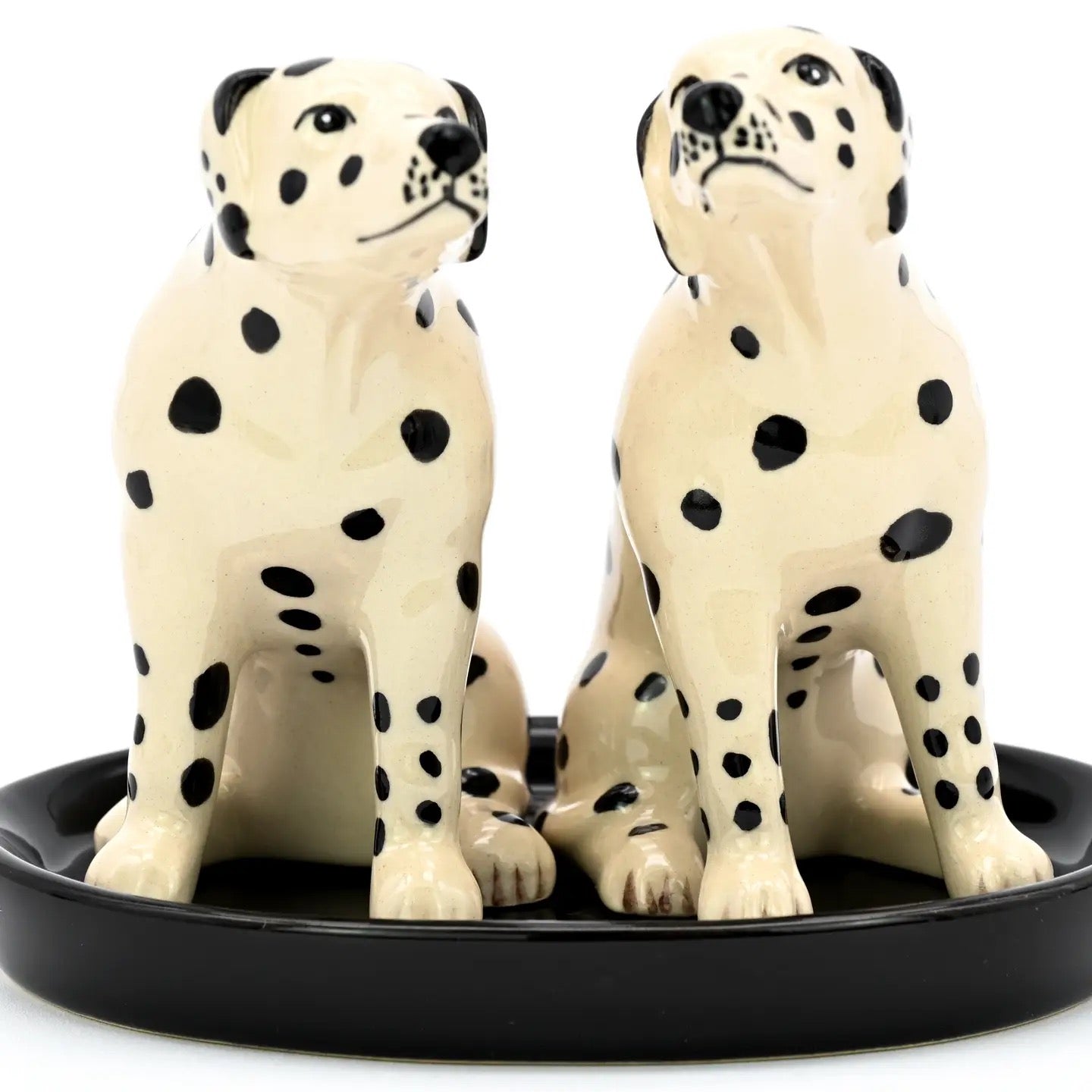 Two ceramic Dalmatian dog figurines on a black base against a white background