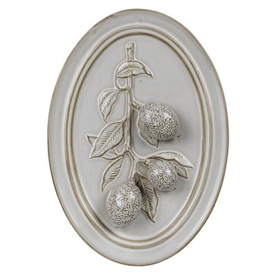 An oval wall plaque featuring a raised relief design of three textured oranges on a branch with leaves, finished in a light gray stone or plaster look with a warm beige border.