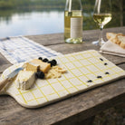 Cheeseboard with assorted cheeses and blackberries on a wooden table by a lake.