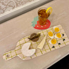 Small ceramic cutting board with cheese and eggs on a gray surface