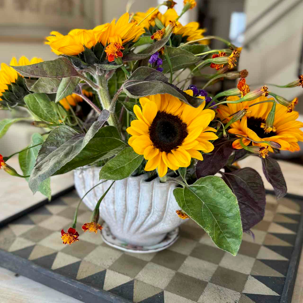 Bouquet of sunflowers in a white vase on a checkered floor
