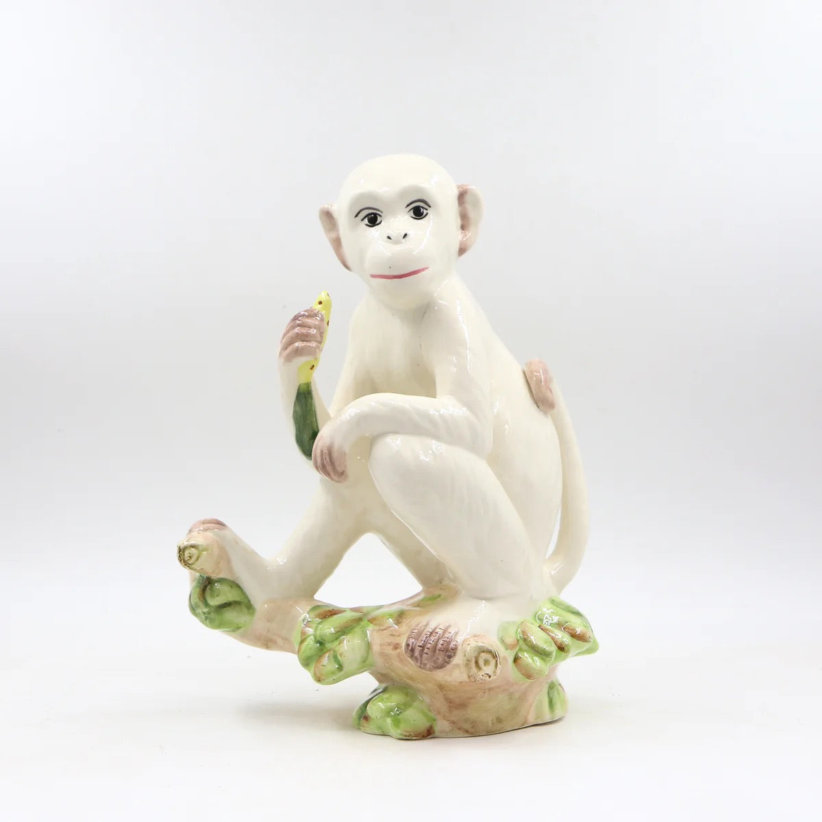 White monkey figurine holding a banana on a white background