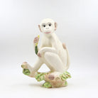 White monkey figurine holding a banana on a white background