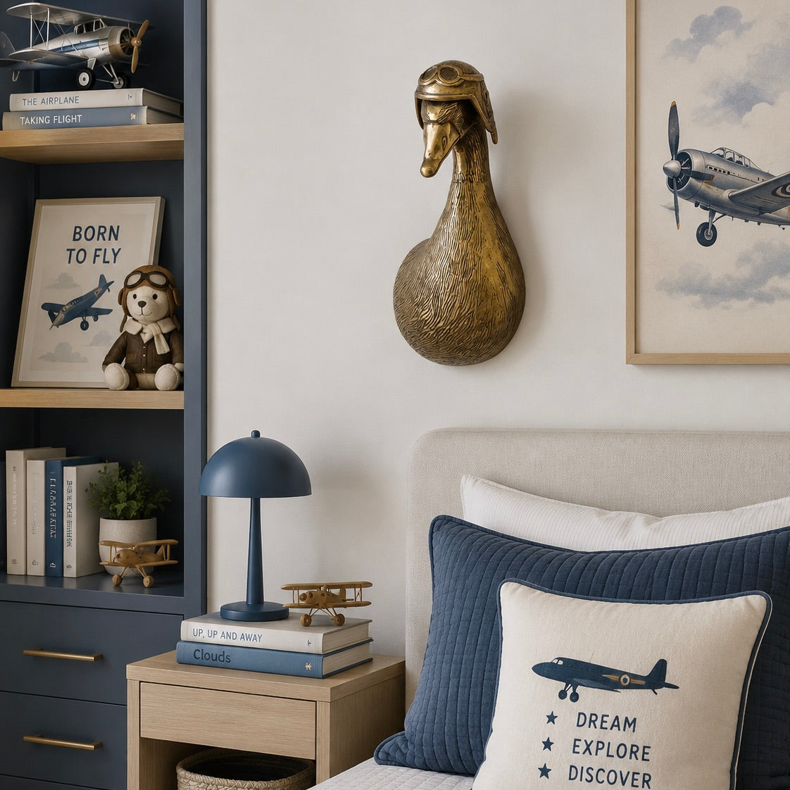 Decorative bedroom with airplane-themed pillows, books, and a lamp.