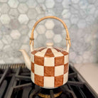 Checkered teapot with wooden handle on a stove